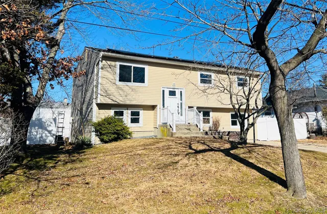 a view of a white house with a large tree