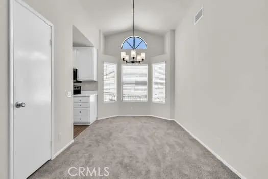 a view of an empty room with window and cabinet area