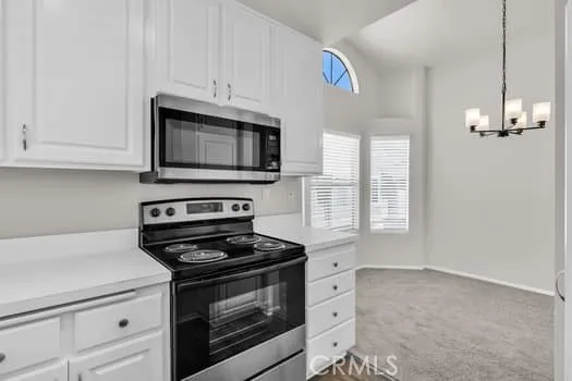a kitchen with granite countertop white cabinets appliances and a window