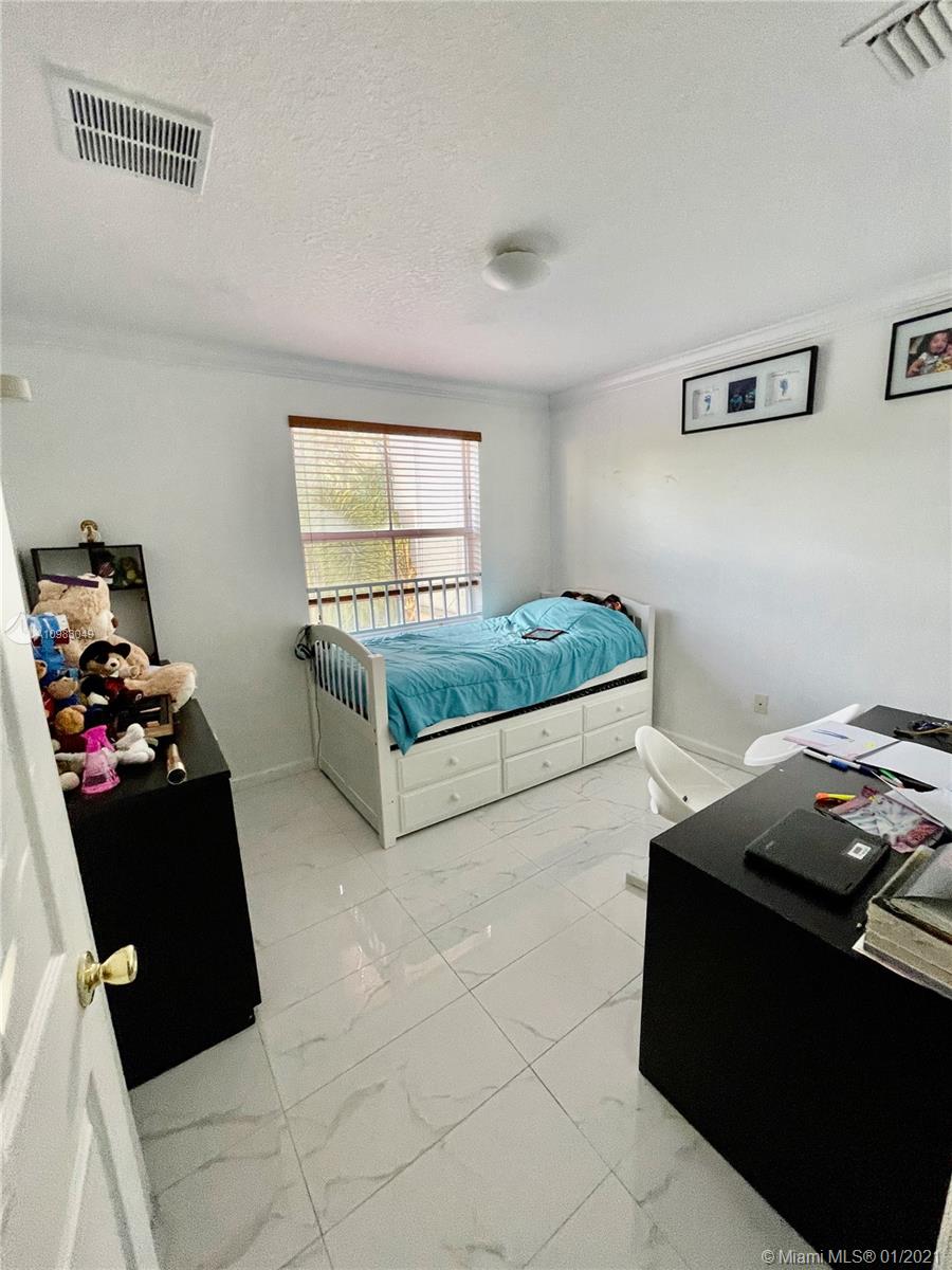 16237 Southwest 48th Street Miramar, FL 33027 - Photo 18 of 28 a bedroom with a bed and dresser
