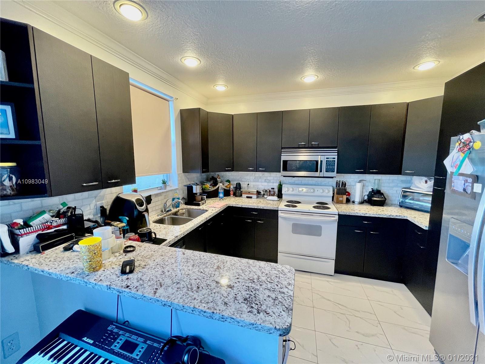 16237 Southwest 48th Street Miramar, FL 33027 - Photo 6 of 28 a kitchen with a sink refrigerator and microwave