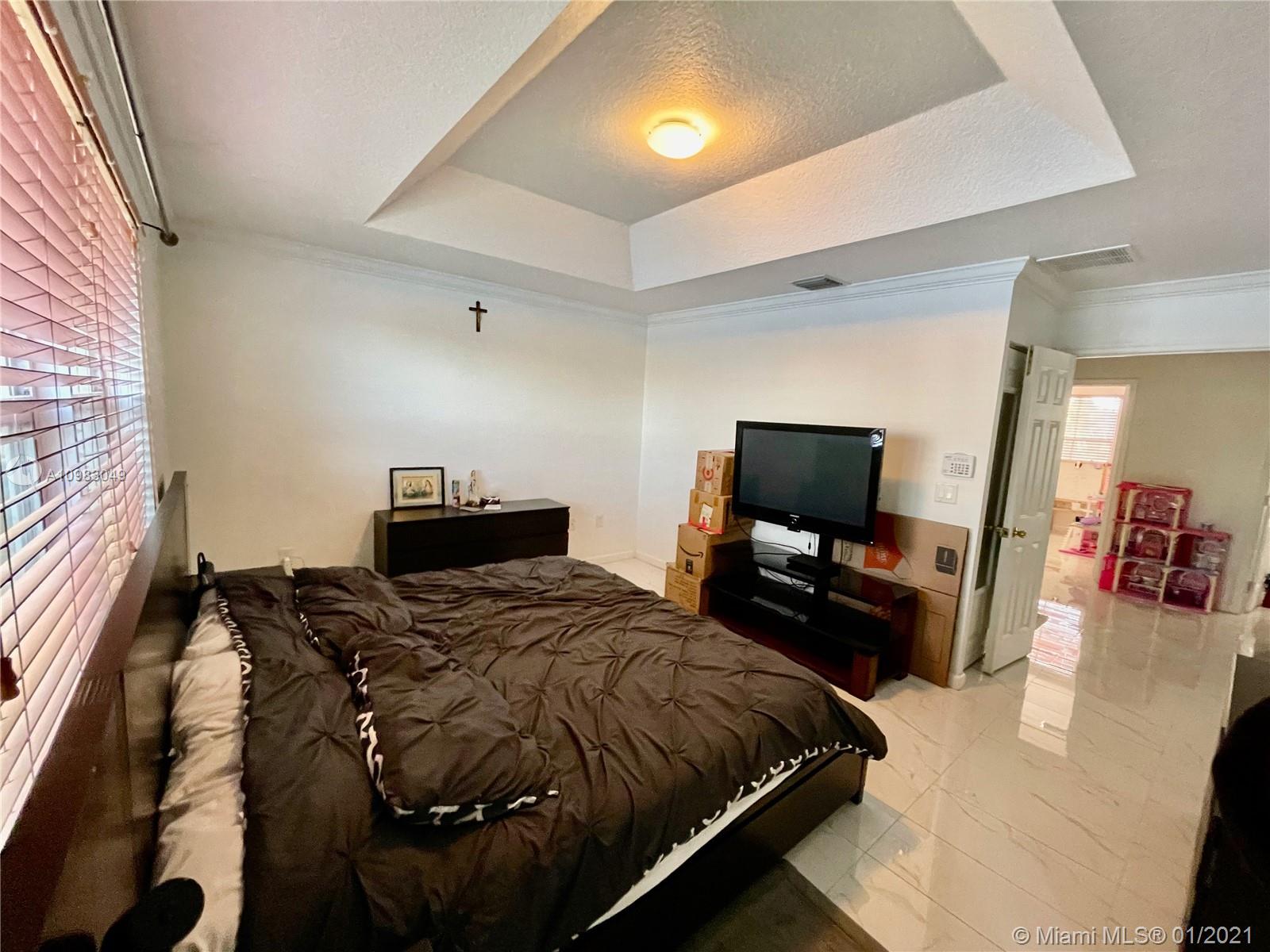 16237 Southwest 48th Street Miramar, FL 33027 - Photo 9 of 28 a bedroom with a bed and flat screen tv