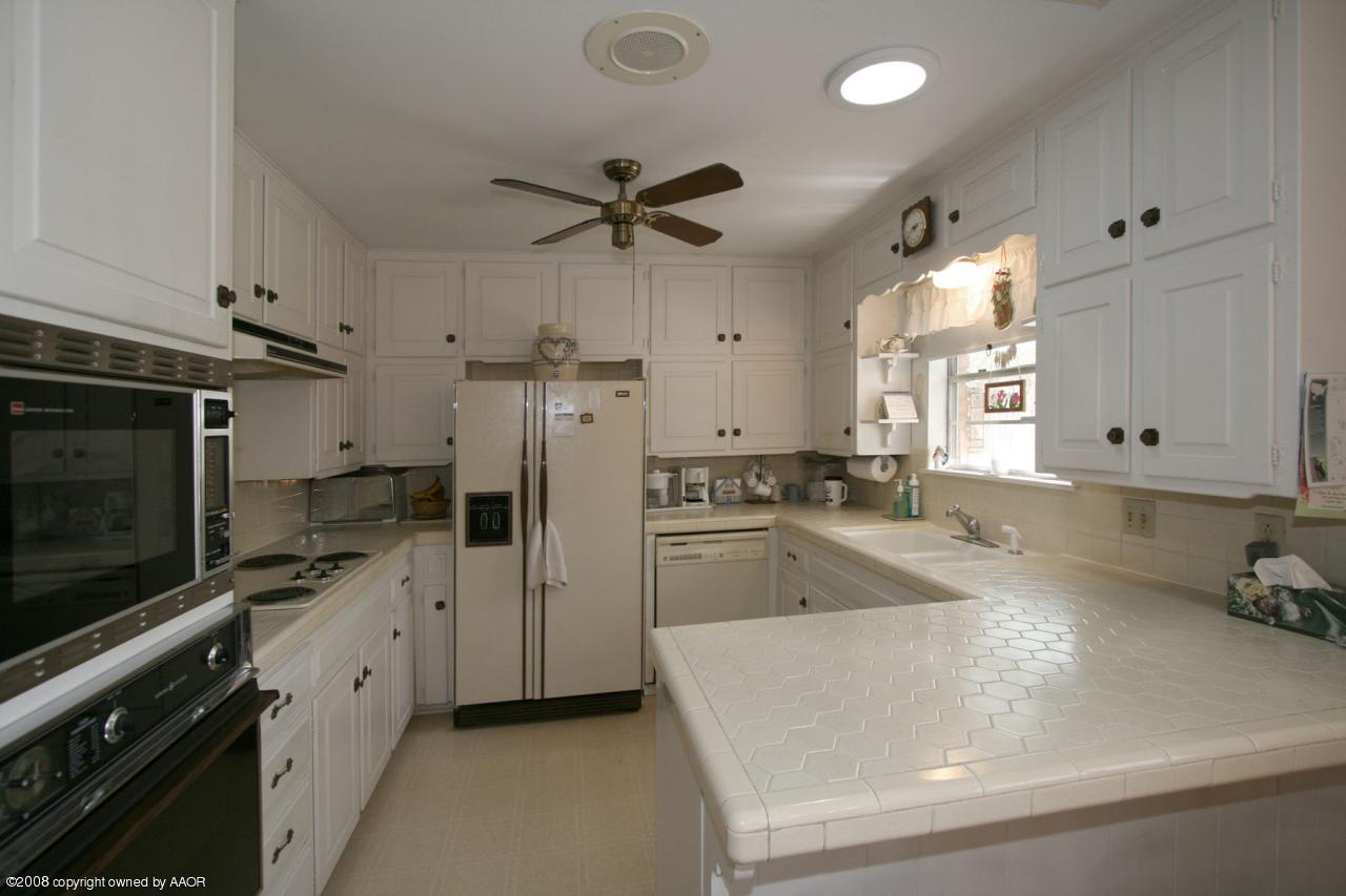 6711 Elmhurst Road Amarillo, TX 79106 - Photo 10 of 15 a kitchen with a refrigerator a sink and cabinets
