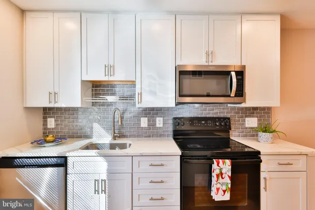 a kitchen with granite countertop white cabinets and black appliances