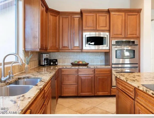 a kitchen with stainless steel appliances granite countertop a sink a stove and a microwave with granite countertops