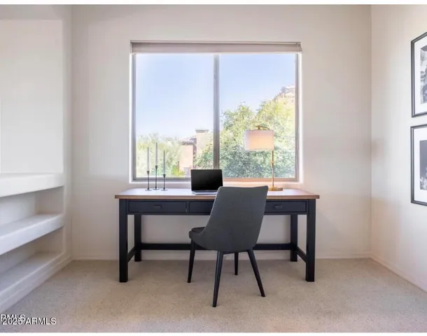 a view of a workspace with furniture and a window