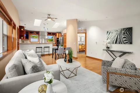 a living room with furniture kitchen view and a wooden floor