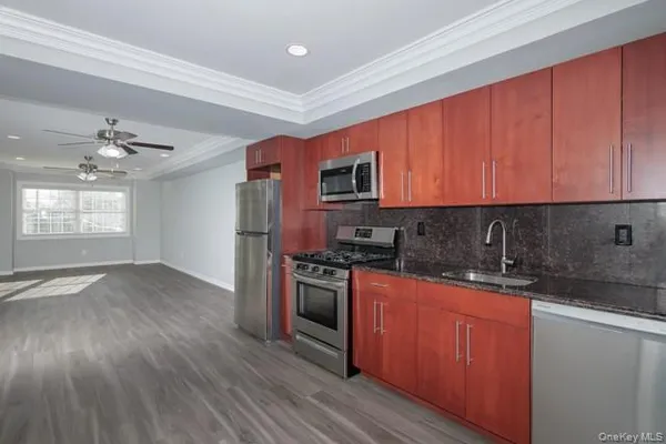 a kitchen with stainless steel appliances granite countertop wooden cabinets a stove a sink and dishwasher with wooden floor