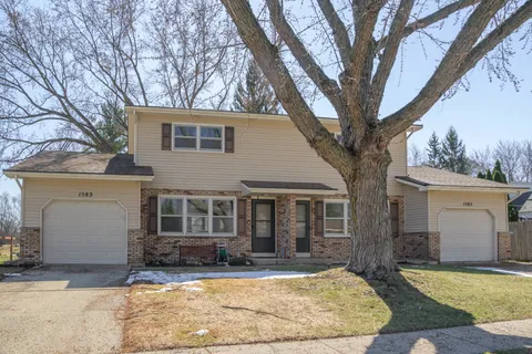 a view of a white house with a large tree and next to a yard