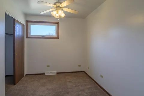 an empty room with a chandelier fan and windows
