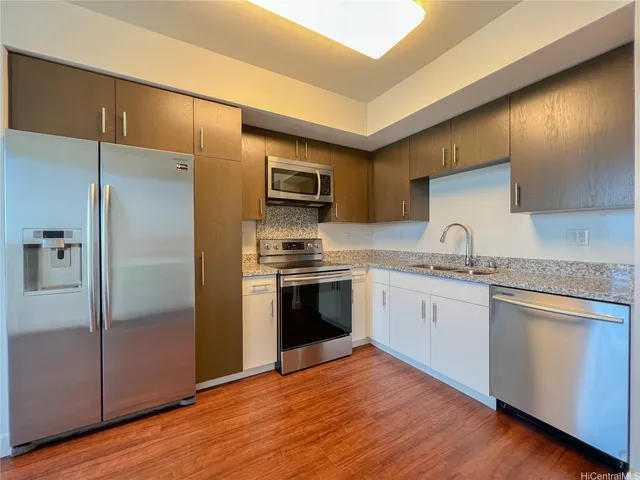 a kitchen with granite countertop a refrigerator stove and sink