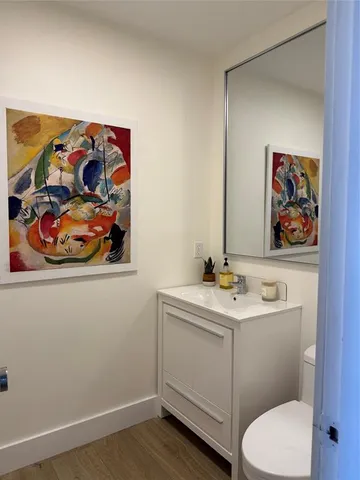 a bathroom with a toilet a sink and wooden floor