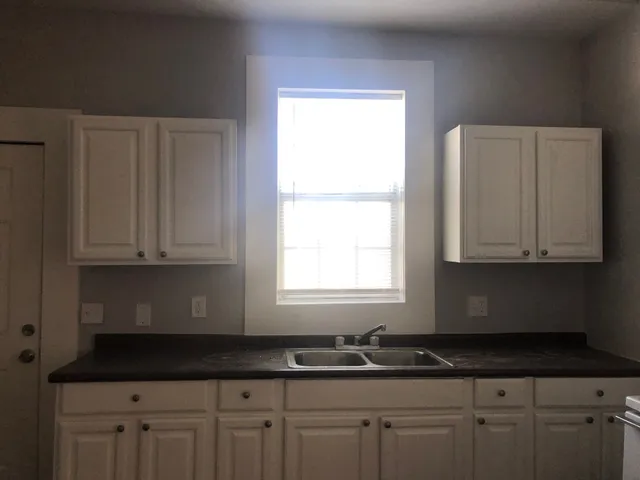 a kitchen with granite countertop white cabinets sink and window