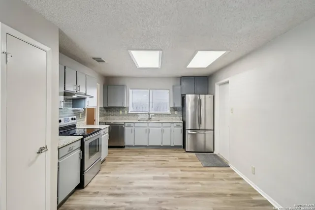 a kitchen with stainless steel appliances granite countertop a refrigerator and a stove top oven