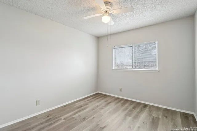 a view of an empty room with closet and a ceiling fan