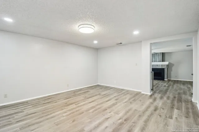 an empty room with wooden floor and view of kitchen