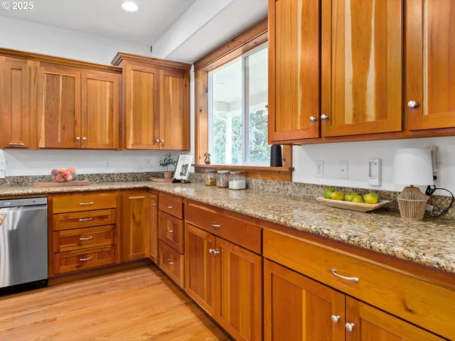a kitchen with granite countertop wooden cabinets a sink and a window