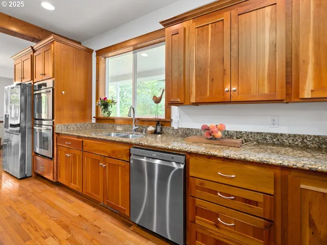 a kitchen with granite countertop wooden cabinets stainless steel appliances a sink and a window