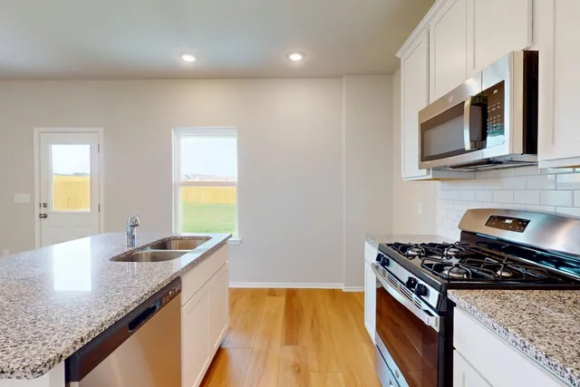 a kitchen with stainless steel appliances granite countertop a sink stove and microwave