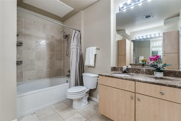 a bathroom with a granite countertop sink a toilet a mirror and bathtub