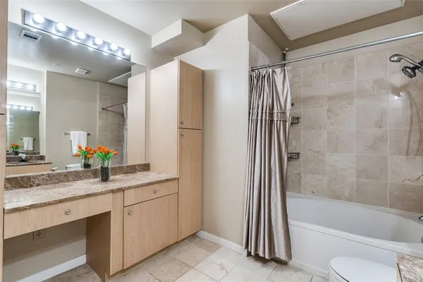 a bathroom with a granite countertop sink a toilet a mirror and shower