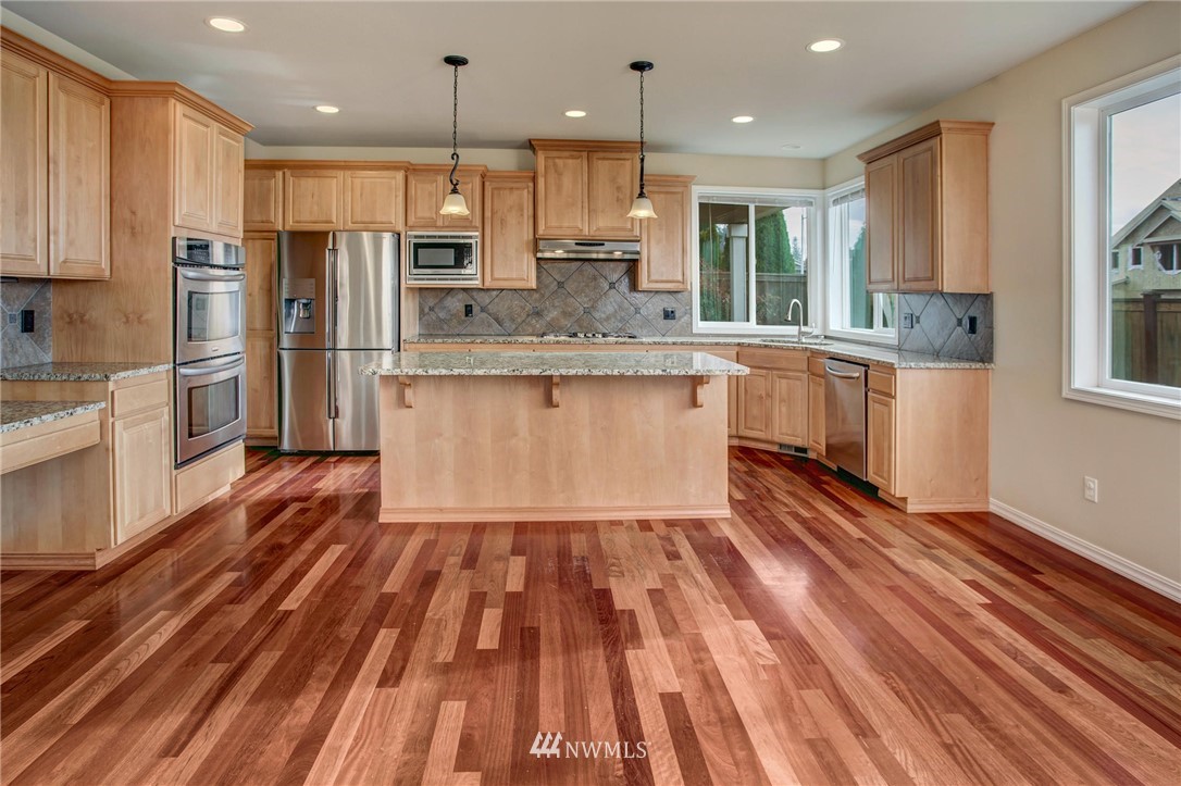 4014 215th Street Southeast Bothell, WA 98021 - Photo 7 of 25 a kitchen with stainless steel appliances granite countertop a refrigerator a sink dishwasher a stove and white countertops with wooden floor