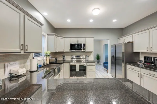 a kitchen with stainless steel appliances a stove a sink a refrigerator a center island and cabinets