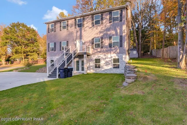a view of a big house with a big yard and large trees