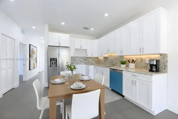 a kitchen with stainless steel appliances granite countertop a sink a stove a dining table and chairs