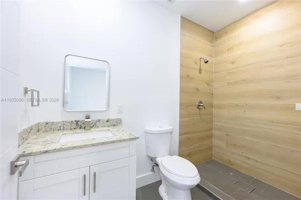 a bathroom with a granite countertop sink toilet a mirror and shower