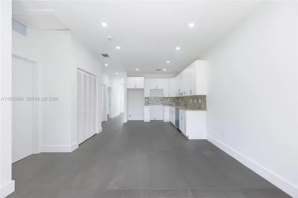 a view of kitchen with refrigerator and white cabinets