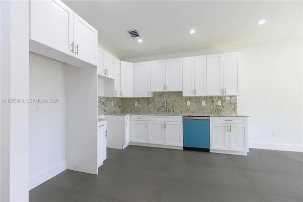a kitchen with granite countertop white cabinets and white stainless steel appliances