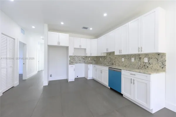 a kitchen with granite countertop white cabinets and stainless steel appliances
