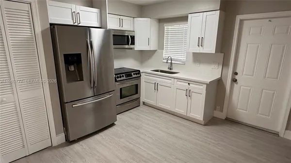 a kitchen with stainless steel appliances a refrigerator sink and microwave