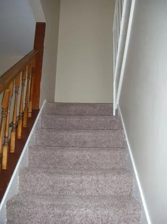 a view of staircase with railing and white walls
