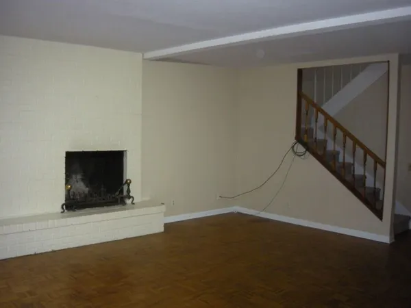 a view of an empty room with wooden floor and a fireplace