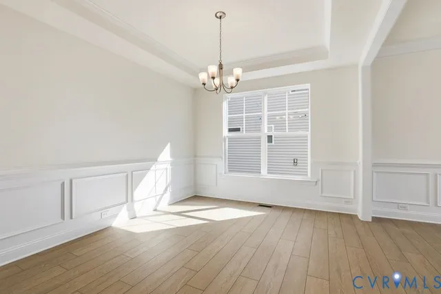 an empty room with wooden floor staircase and windows