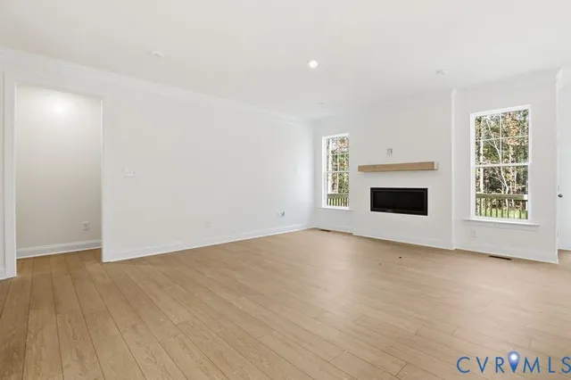 a view of empty room with wooden floor and fireplace