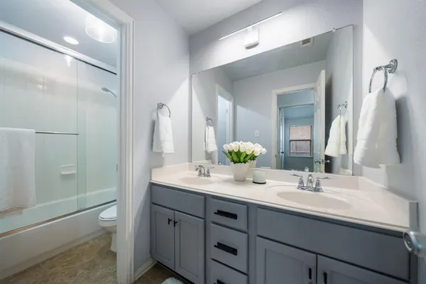a bathroom with a double vanity sink toilet and shower