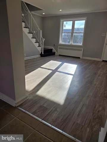 a view of an empty room with wooden floor and windows
