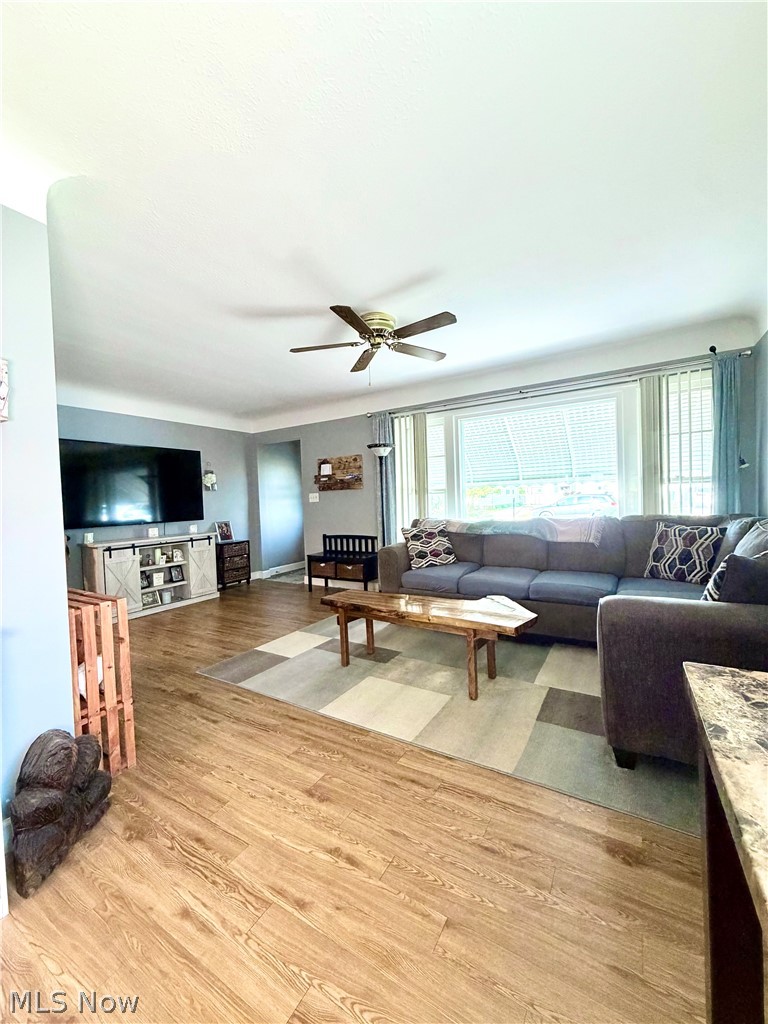 32125 Densmore Road Willowick, OH 44095 - Photo 4 of 23 Spacious living area featuring wood-finish flooring, a ceiling fan, and a large bay window with horizontal blinds