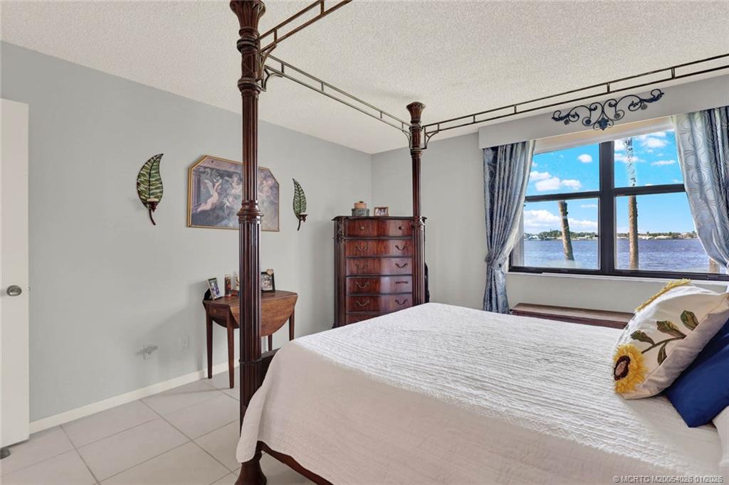 1950 Southwest Palm City Road, Unit 8106 Stuart, FL 34994 - Photo 28 of 54 a bedroom with a bed and a chandelier