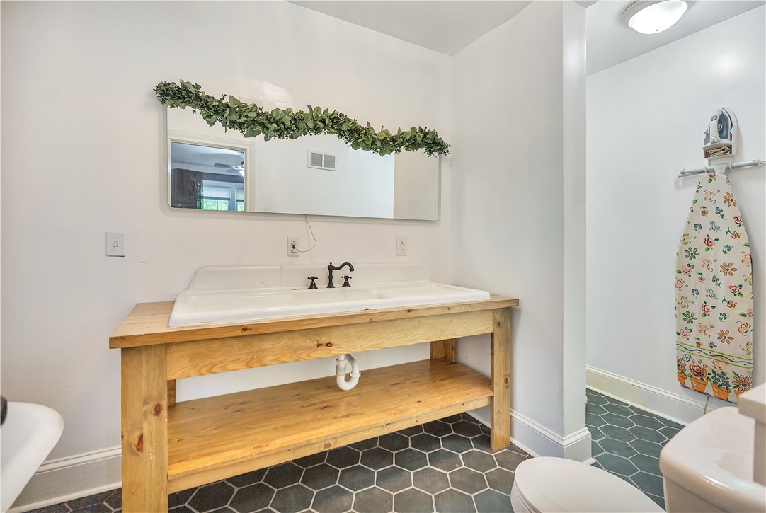 25 Central Avenue Honea Path, SC 29654 - Photo 16 of 36 This bathroom features a functional vanity with a sleek mirror and a toilet, perfect for daily routines.