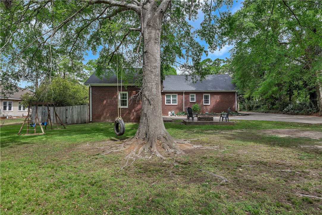 25 Central Avenue Honea Path, SC 29654 - Photo 26 of 29 This expansive backyard offers ample space for recreation and relaxation, framed by mature trees and a charming brick residence.