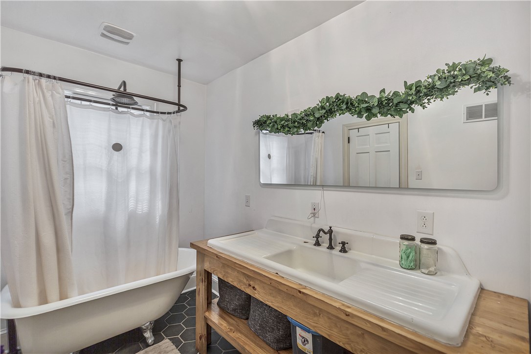 25 Central Avenue Honea Path, SC 29654 - Photo 7 of 29 This bathroom features a vintage-inspired clawfoot tub and a spacious vanity with a trough sink.