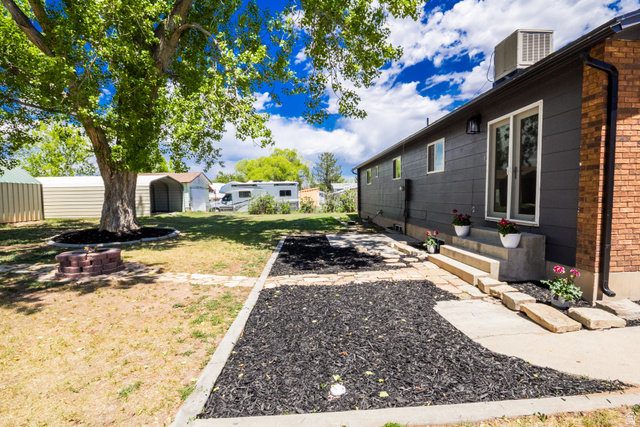 634 South 2100th Street West Vernal, UT 84078 - Photo 52 of 71 Expansive backyard featuring a mature tree, brick-ringed fire pit, and a patio with concrete steps