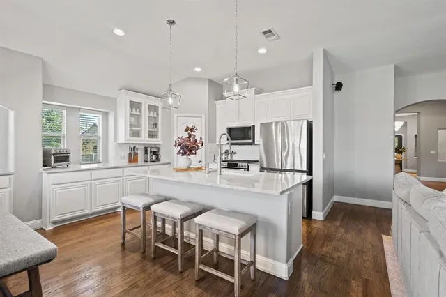 a kitchen with stainless steel appliances a refrigerator a stove a dining table and chairs