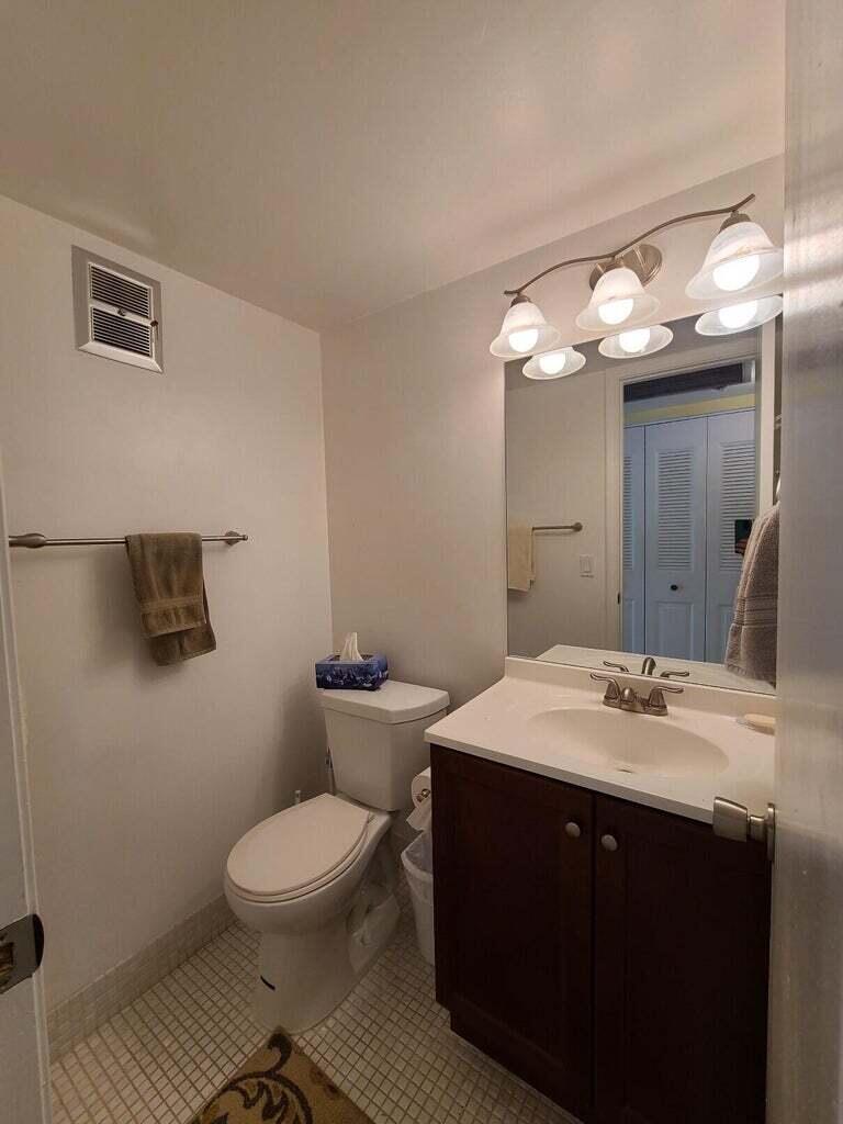 133 Camden East, Unit F West Palm Beach, FL 33417 - Photo 9 of 13 a bathroom with a toilet a sink and mirror