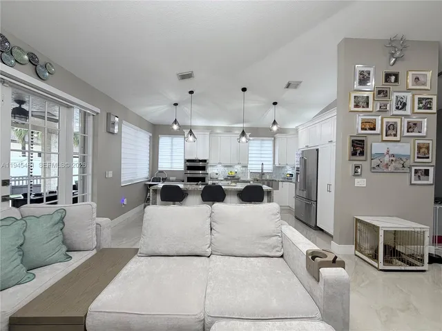 a kitchen with stainless steel appliances granite countertop a stove a sink dishwasher a stove a refrigerator and white cabinets with wooden floor