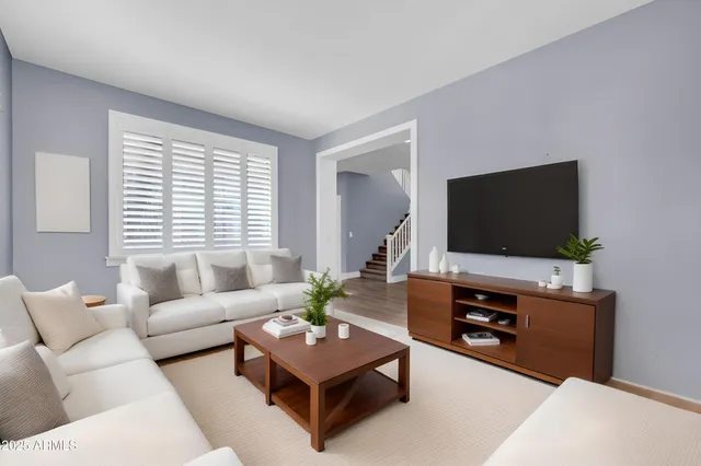 a living room with furniture a flat screen tv and a wooden floor